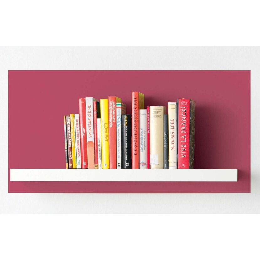 Kochbücher auf einem weißen Regal vor weinroter Wand