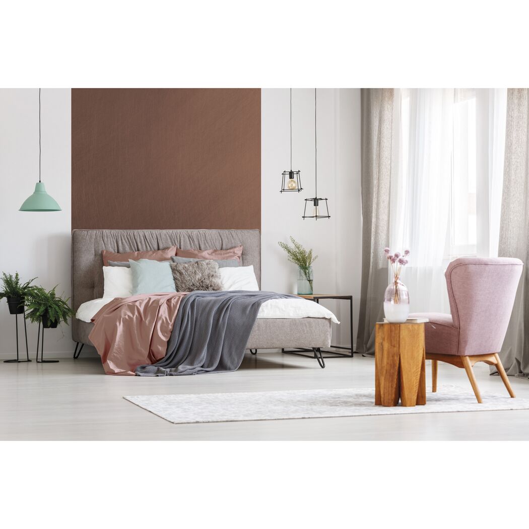 Schlafzimmer mit Bett, Sessel, Lampe, Teppich und Pflanzen