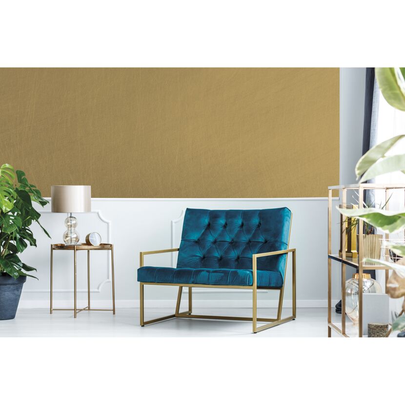 Wohnzimmer mit goldener Wand und blauem Sessel