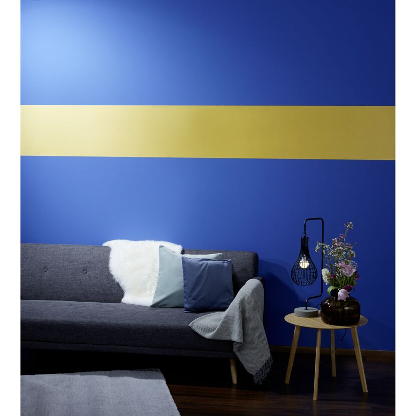 Blaue Wand mit goldfarbenem Streifen, Sofa und Beistelltisch