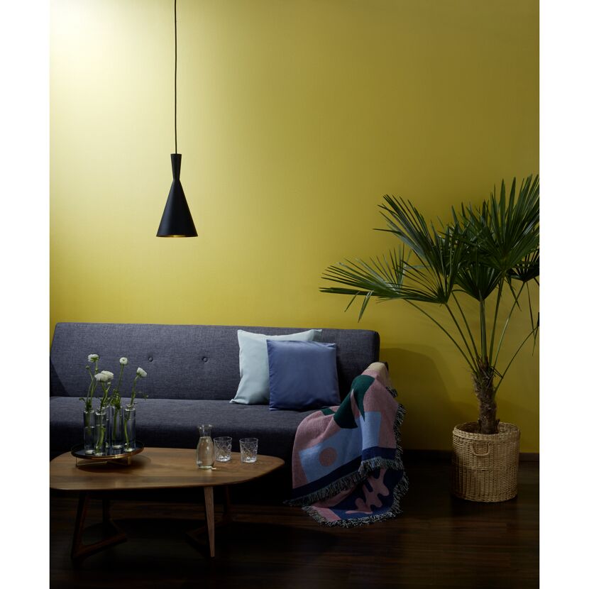 Wohnzimmer mit senfgelber Wand und schwarzer Hängelampe