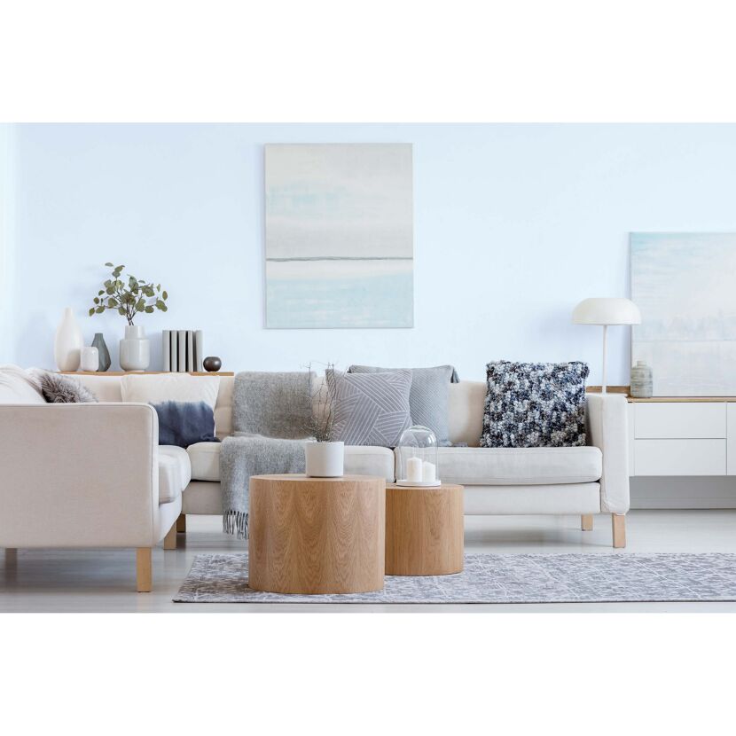 Modernes Wohnzimmer mit beiger Couch, Holztischen und hellblauer Wand