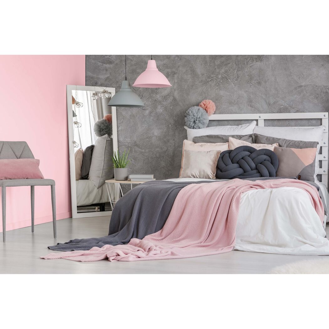 Schlafzimmer mit Bett, Spiegel, Stuhl und rosa und grauer Deko