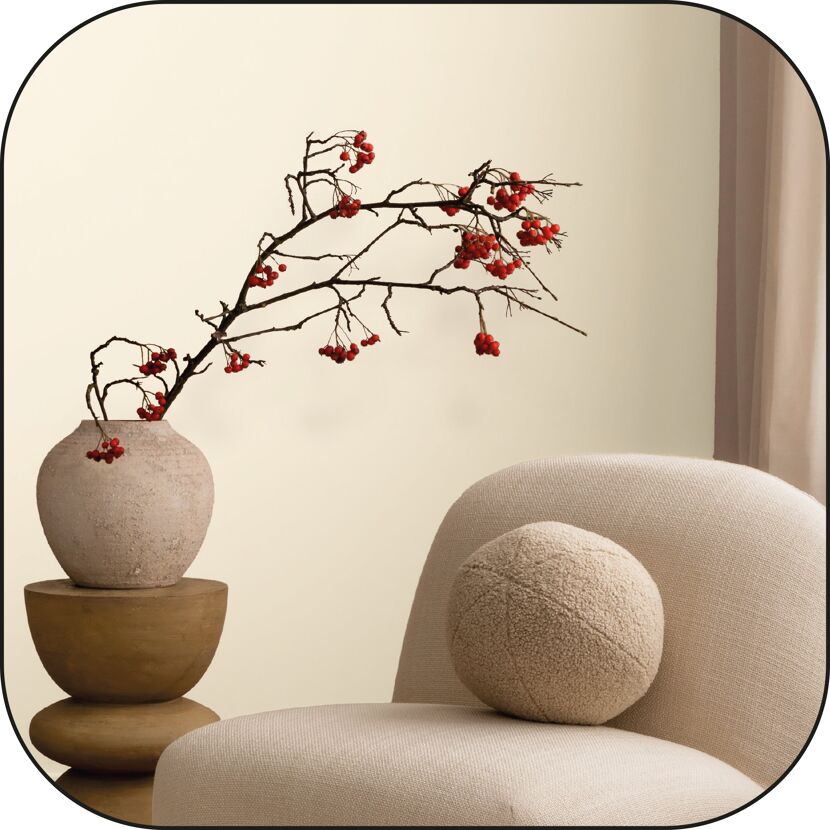 Beiger Sessel mit Kissen, Vase mit roten Beeren