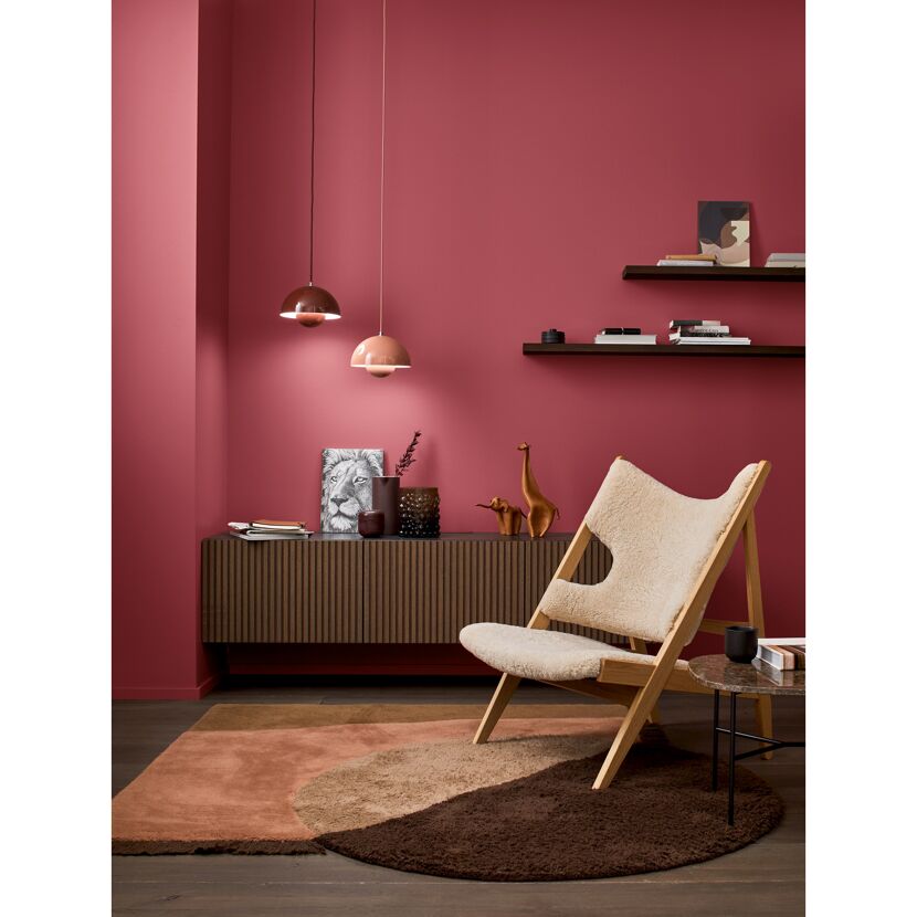 Wohnzimmer mit beerenroter Wand und gemütlichem Sessel