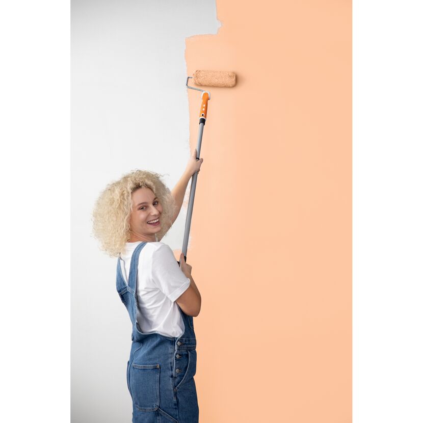 Person streicht eine Wand mit Farbrolle
