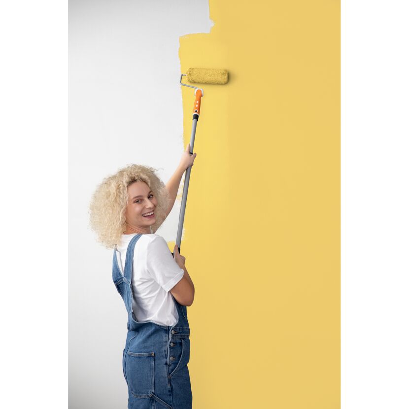 Person streicht Wand mit Farbrolle gelb