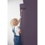 Person streicht eine Wand mit violetter Farbe.