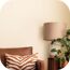 Sofa, Lampe und Pflanze vor beigefarbener Wand