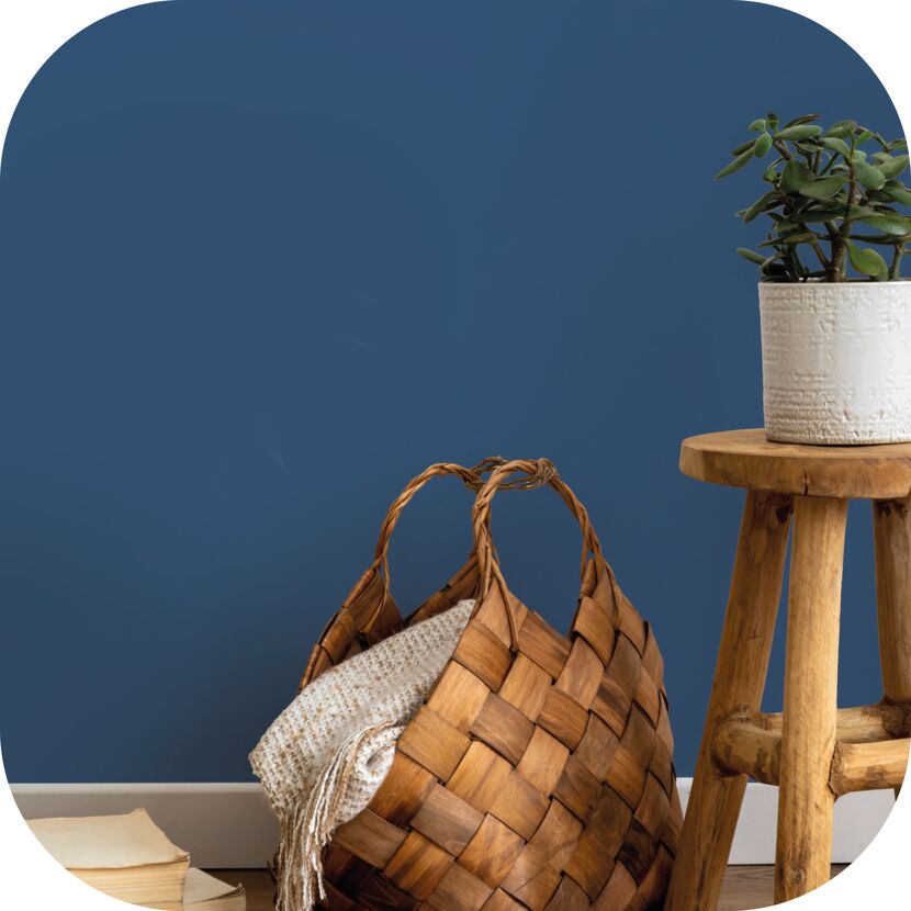 Holzkorb, Hocker und Pflanze vor blauer Wand