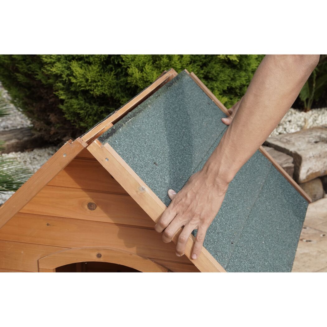 Person baut ein Hundehaus aus Holz zusammen.