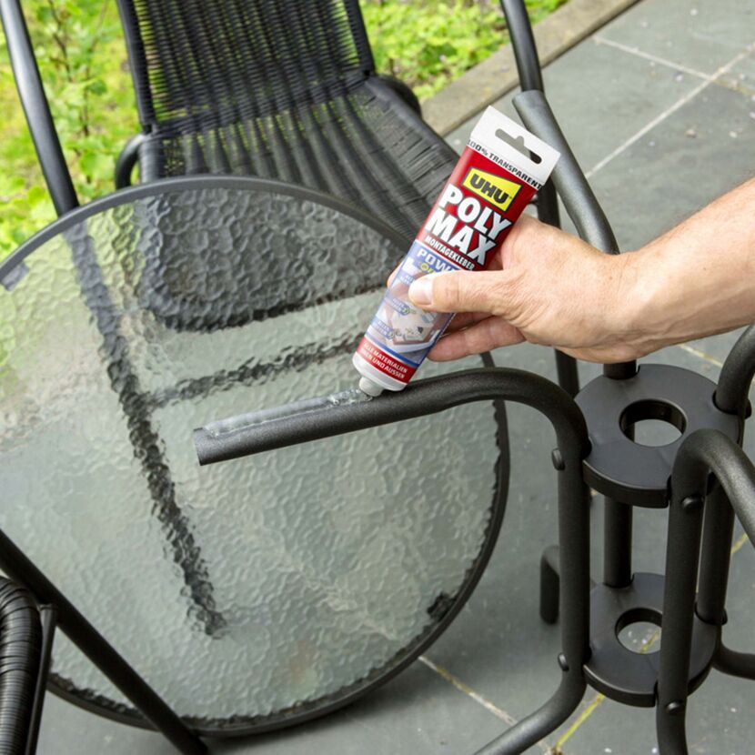 Person klebt einen schwarzen Gartenstuhl mit UHU Poly Max.