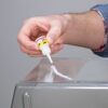 Person klebt eine durchsichtige Oberfläche mit UHU Sekundenkleber.