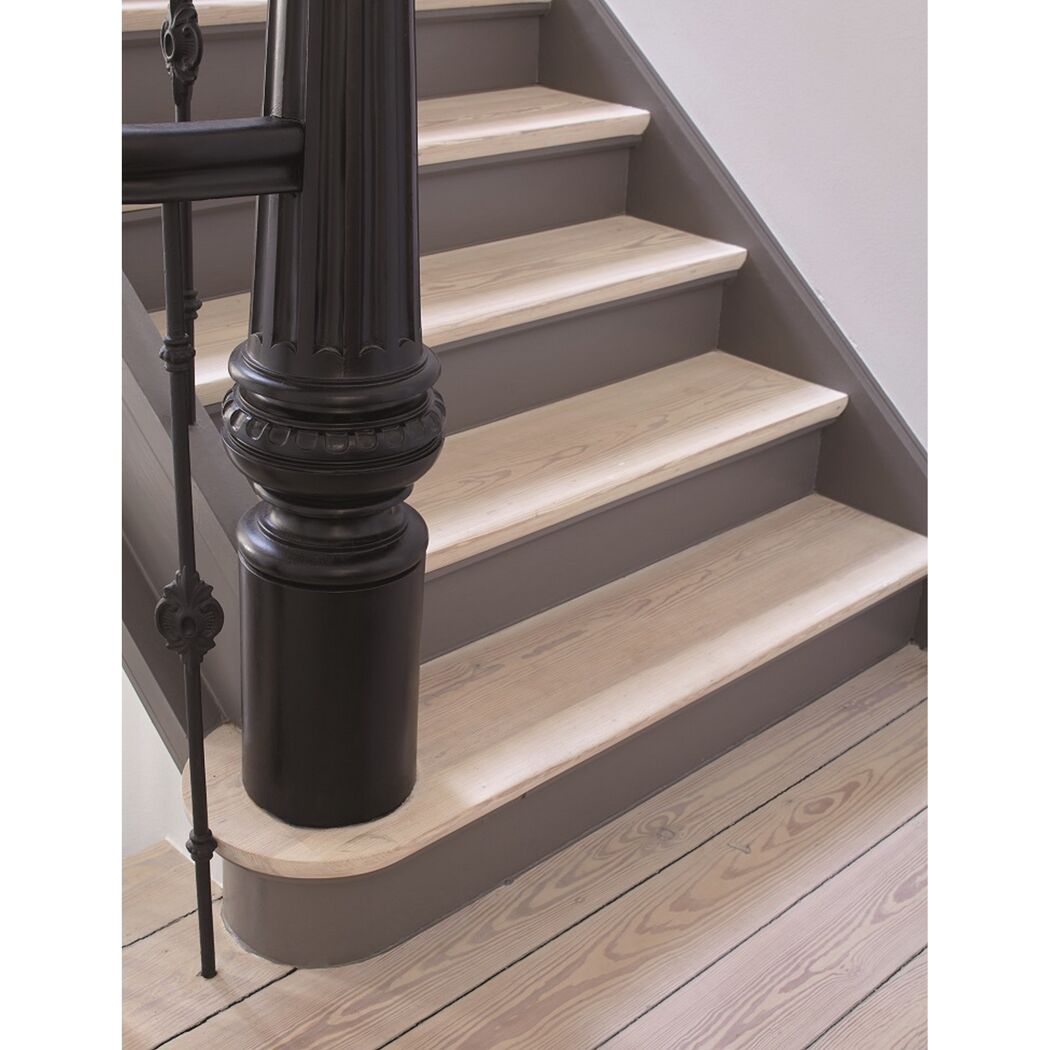 Detail einer Holztreppe mit schwarzem Treppengeländer.