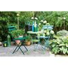 Zwei grüne und ein blauer Klappstuhl, ein Tisch und Deko im Garten.