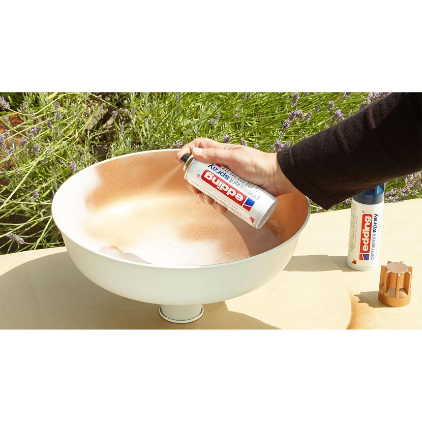 Person besprüht eine Schale mit edding Permanentspray kupfer.