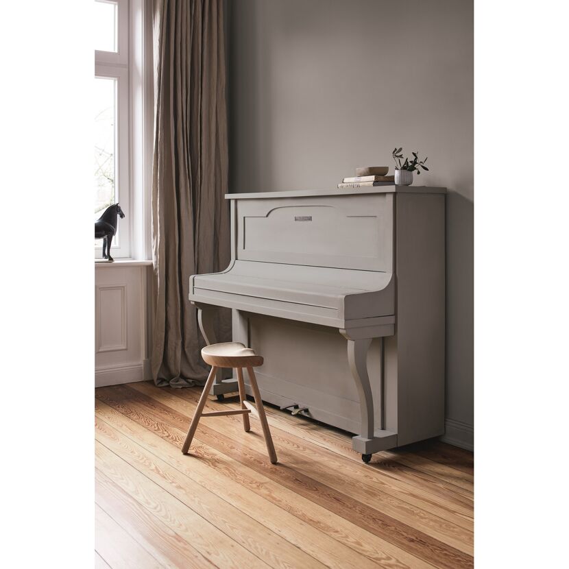 Graues Klavier mit Hocker in einem Raum.