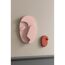 Rosa und rotbraune abstrakte Gesichtsformen an beigefarbener Wand.