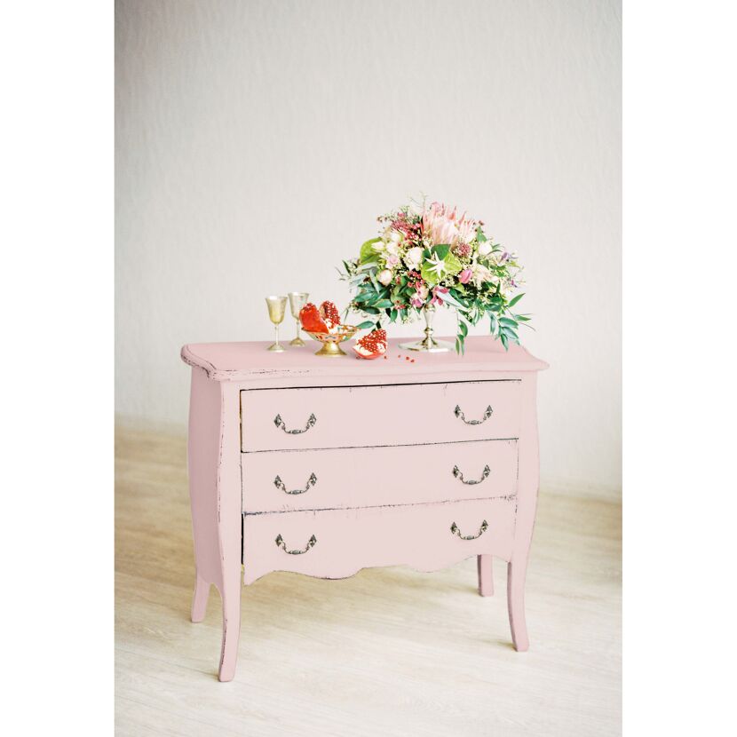 Rosa Kommode mit Blumenstrauß und Granatapfel
