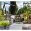 Graue Gartenschaukel auf Terrasse mit Grill und Sonnenblumen