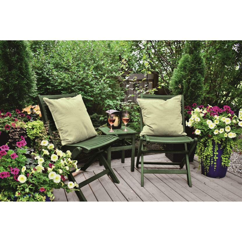 Zwei Gartenstühle mit Kissen und Getränke auf einem Tisch auf einer Terrasse
