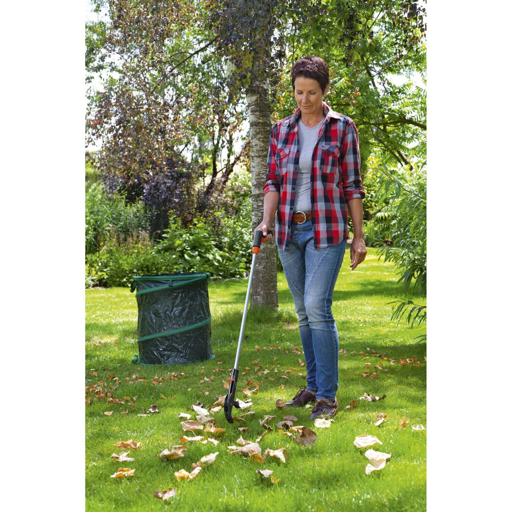 Person sammelt mit einem Abfallgreifer Laub im Garten.