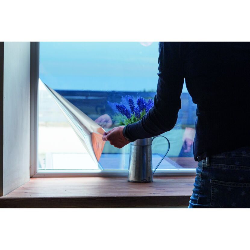 Person bringt Spiegelsichtschutzfolie am Fenster an