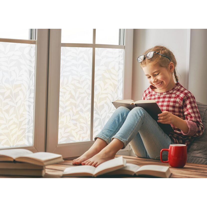 Kind liest vergnügt ein Buch am Fenster.