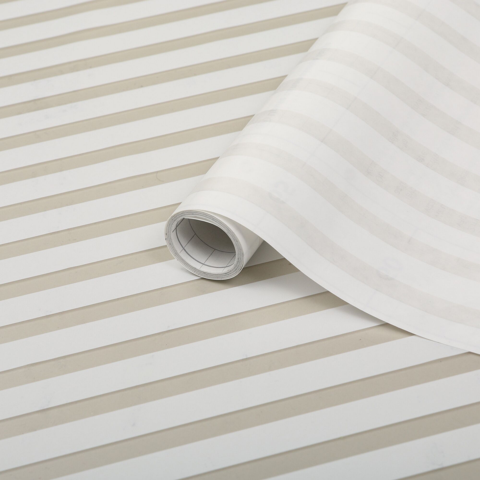 Weiße Klebefolie mit hellbeigen Streifen auf Rolle