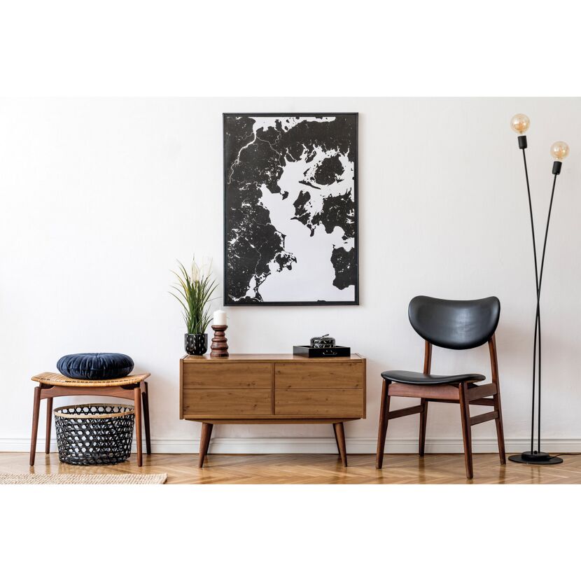 Wohnzimmer mit Holzkommode, Korbstuhl und schwarz-weißem Bild