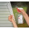 Person bringt mit Sprühflasche Fensterfolie an.