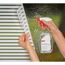 Person bringt mit Sprühflasche Fensterfolie an.