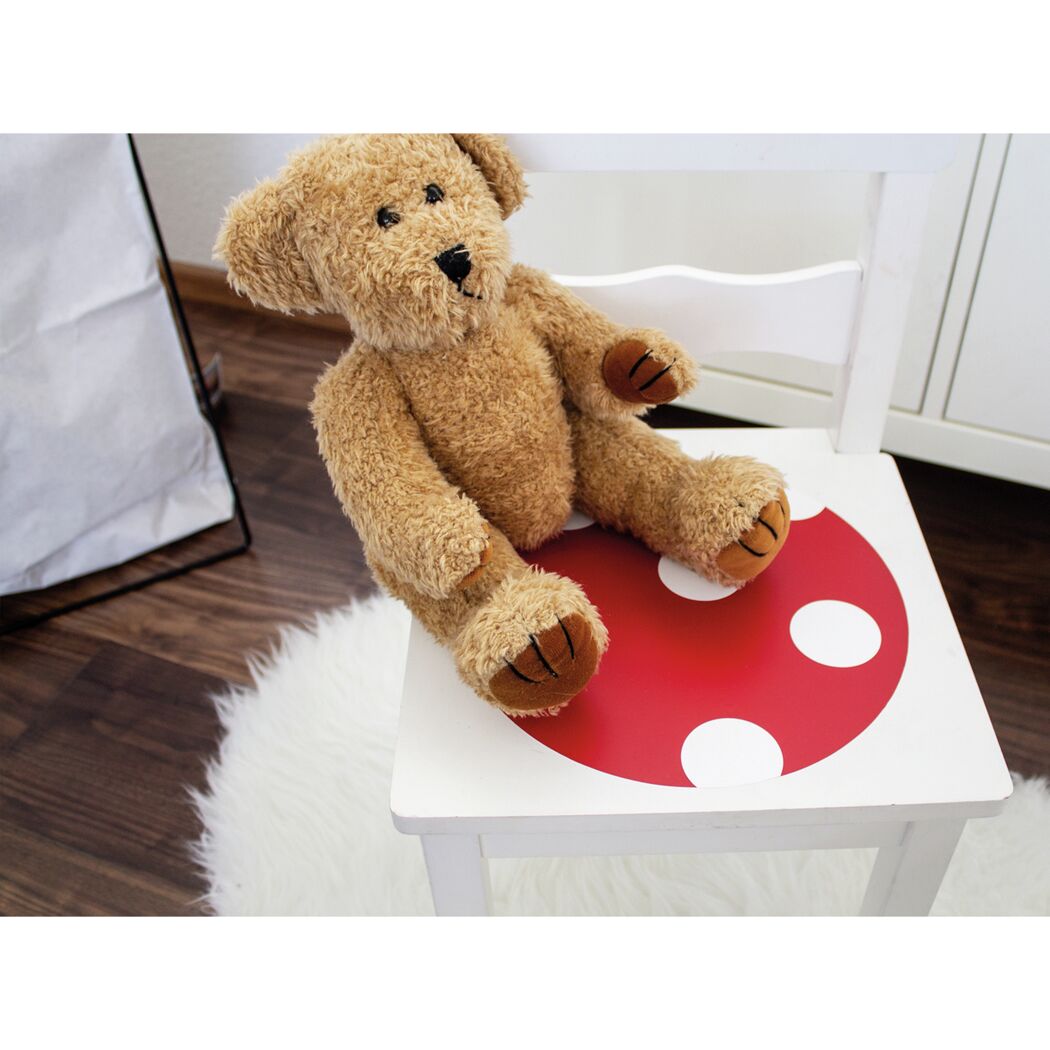 Teddybär auf einem Stuhl mit roter Klebefolie