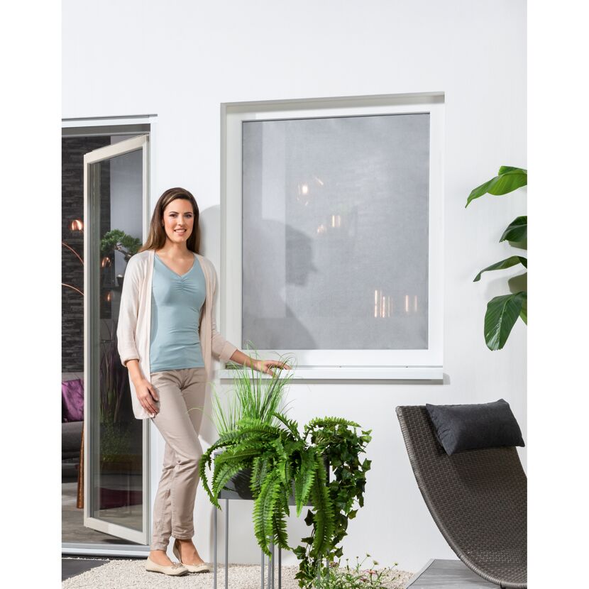 Person lehnt an Hauswand mit Sonnenschutzfolie am Fenster.
