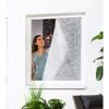 Person bringt Pollenschutzvlies am Fenster an