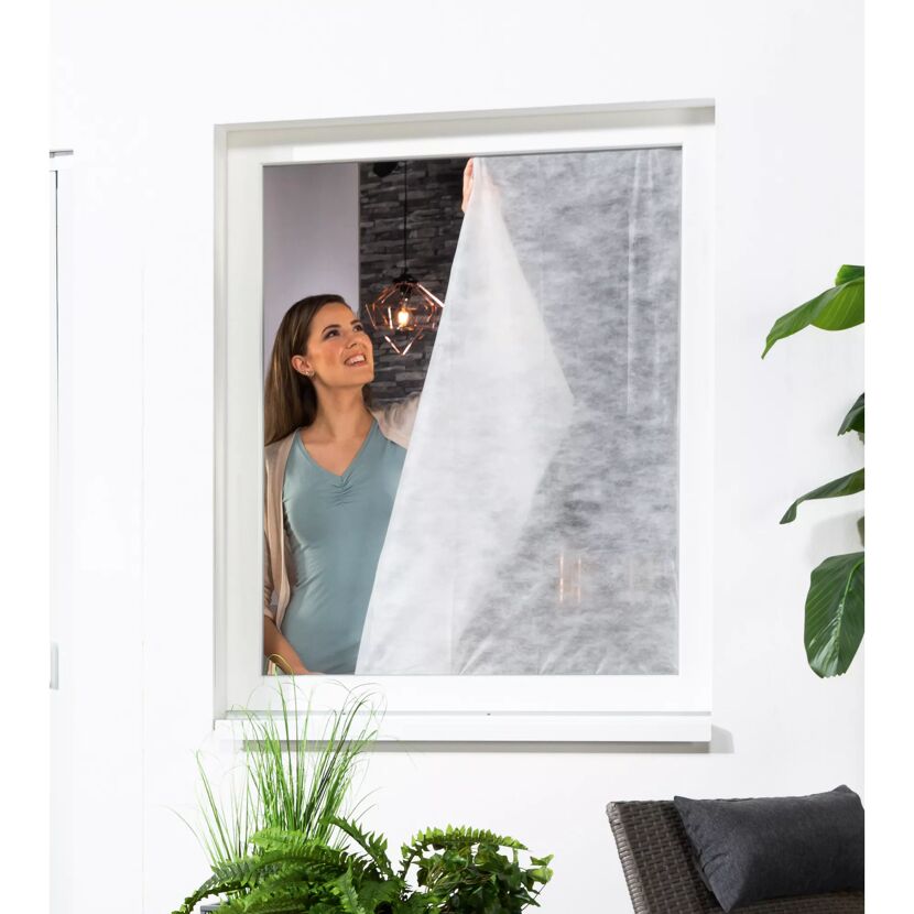 Person bringt Pollenschutzvlies am Fenster an