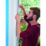 Person bringt Klettband am Fensterrahmen an