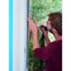 Person bringt Klettband für Fliegengitter am Fenster an.