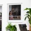 Person schaut durch ein Fenster mit Fliegengitter.