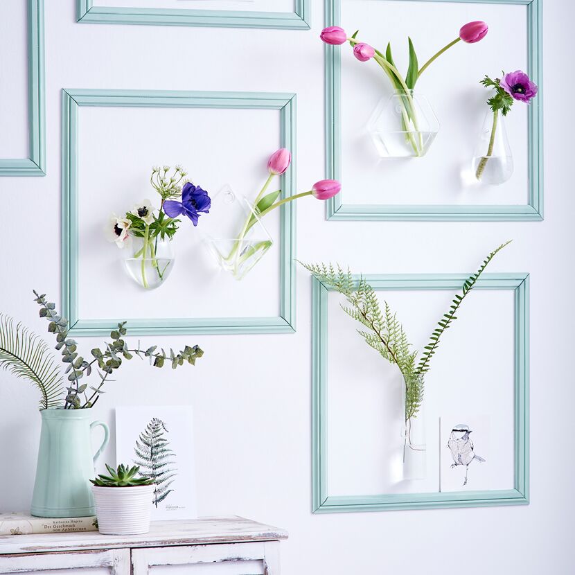 Blumenvasen in Bilderrahmen an der Wand