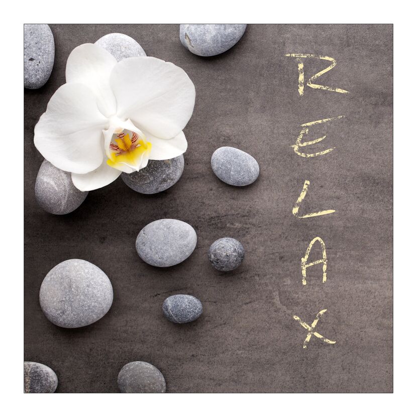 Weiße Orchideenblüte und graue Steine auf Schiefer. Das Wort Relax ist mit Kreide geschrieben.