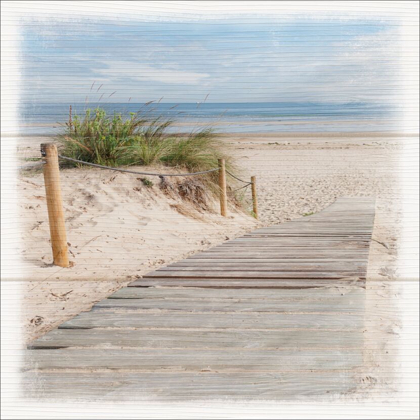 Holzsteg führt über Sanddüne zum Strand.