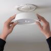 Weiße LED-Deckenleuchte mit Bewegungssensor wird montiert.