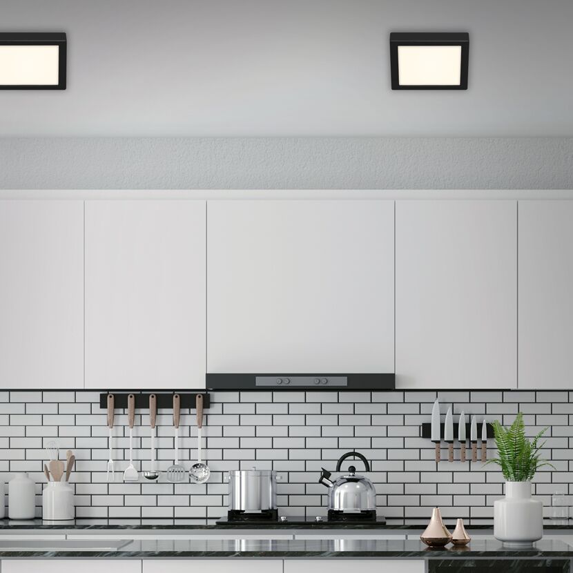 Moderne Küche mit schwarzen Deckenleuchten und weißen Schränken.