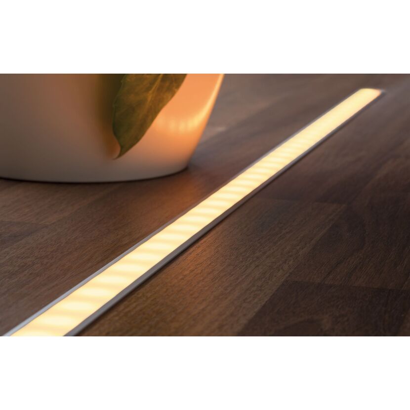 LED-Lichtband leuchtet auf dunklem Holzboden