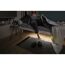 Person steht am Bett auf, unter dem Bett leuchtet ein LED-Strip.