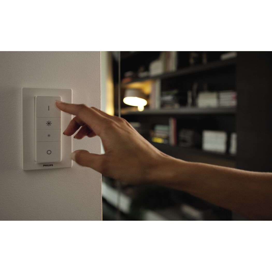 Hand bedient Philips Hue Dimmer an der Wand.