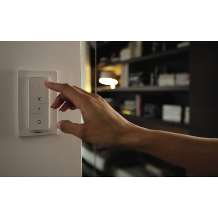 Hand bedient Philips Hue Dimmer an der Wand.