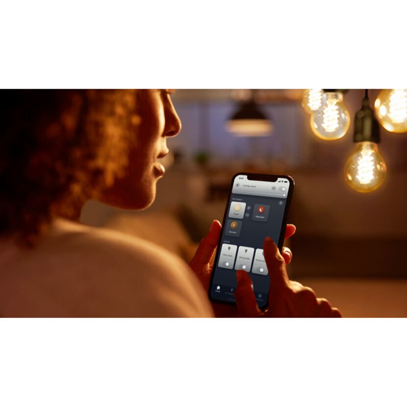 Person steuert Hue LED-Leuchtmittel mit Smartphone.