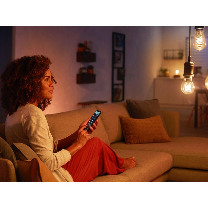 Person steuert Hue White LED-Leuchtmittel mit Smartphone.